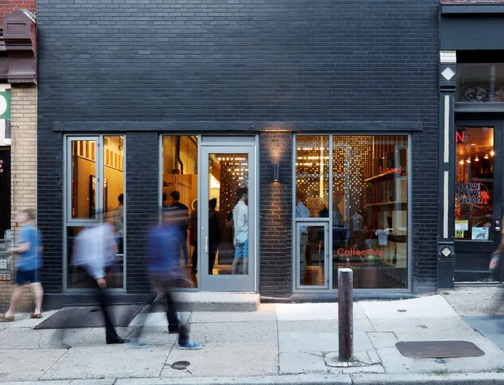 A picture of the GALLERY Land Collective façade with motion-blurred people walking in front of it.
