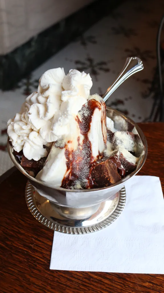 Ice cream sundae with whipped cream in silver dish on counter at The Franklin Fountain