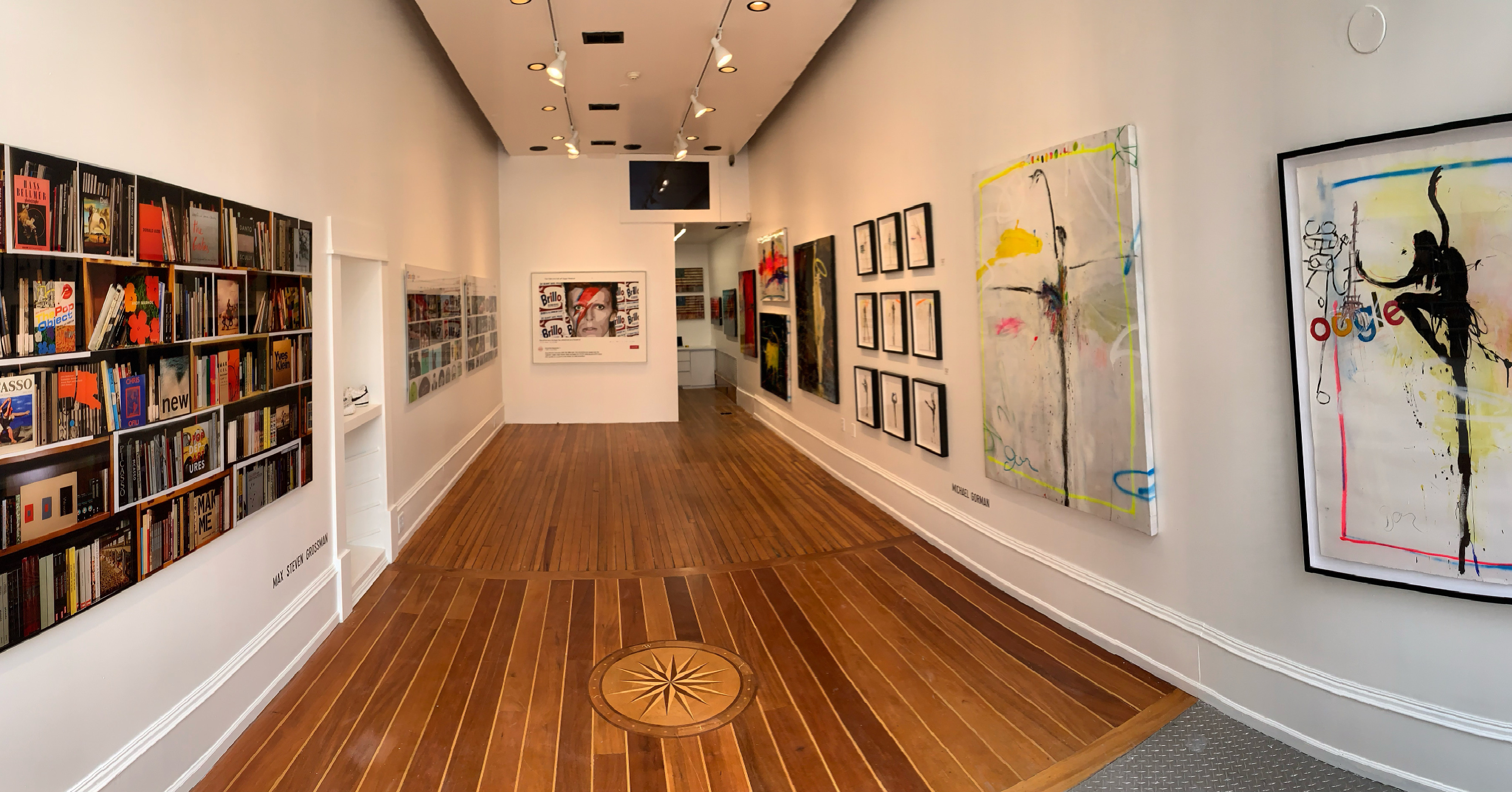 Inside of AXIOM Contemporary art gallery with white walls and artwork on display and a wood floor
