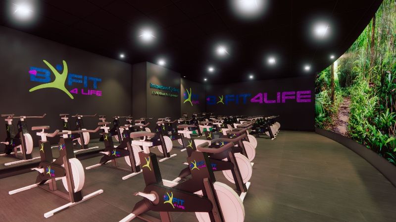 Interior of BFIT4LIFE fitness studio with exercise bikes and a large theater screen