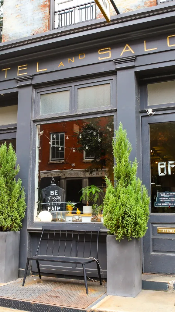 Gray exterior of Lokal Hotel and Barnet Fair along N. 3rd Street in Old City, with four large plants outside salon.