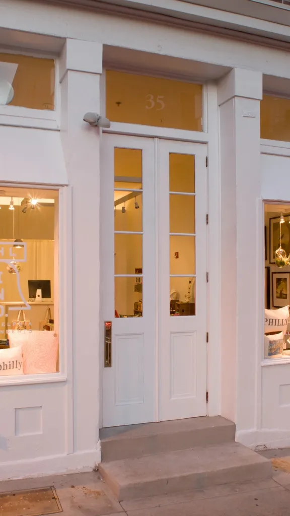 Exterior of store front with two windows of merchandise displays and a door in the middle