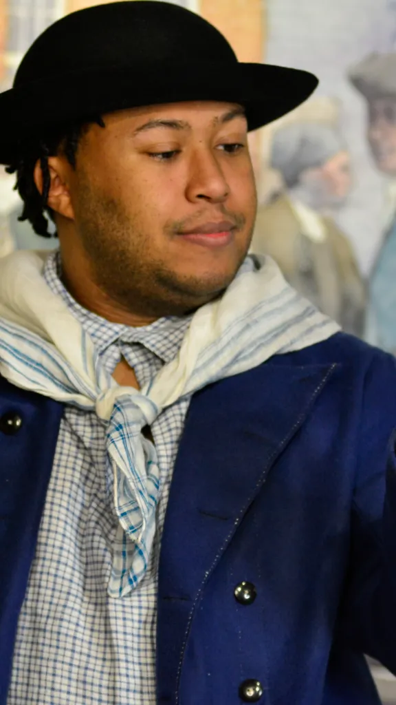 Actor Nathan Alford-Tate depicts a sailor in a blue coat holding a sailmaking fid in our Meet James Forten first-person theatrical performance.