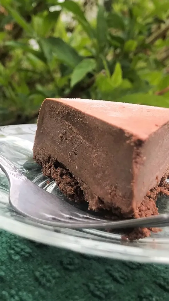 A slice of chocolate cheesecake on a plate with a fork