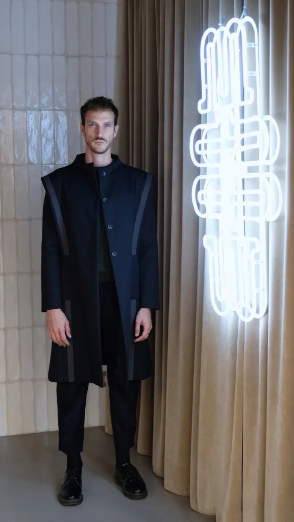 Man in French fashion standing next to a neon light
