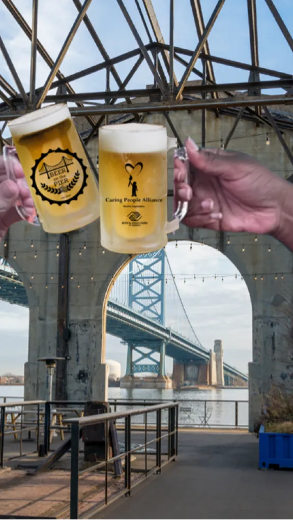 Two people holding up a glass of beer at Cherry Street Pier