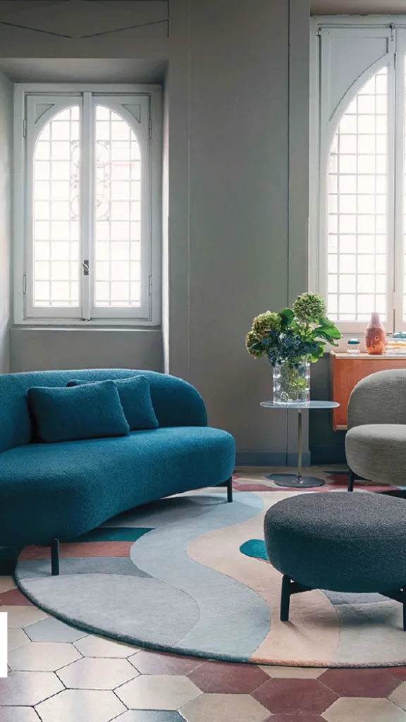kartell furniture on display in a living room including a blue sofa and two gray chairs