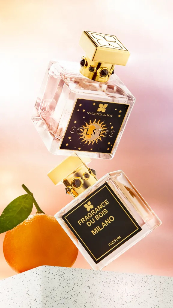 Two bottles of perfume with orange on display behind them