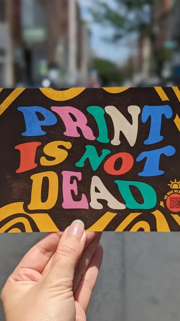 Person holding flyer that says "Print is not dead"