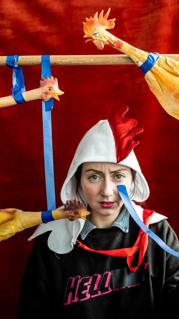 Alex Tatarsky dressed as a rooster amongst rubber chickens and tape.