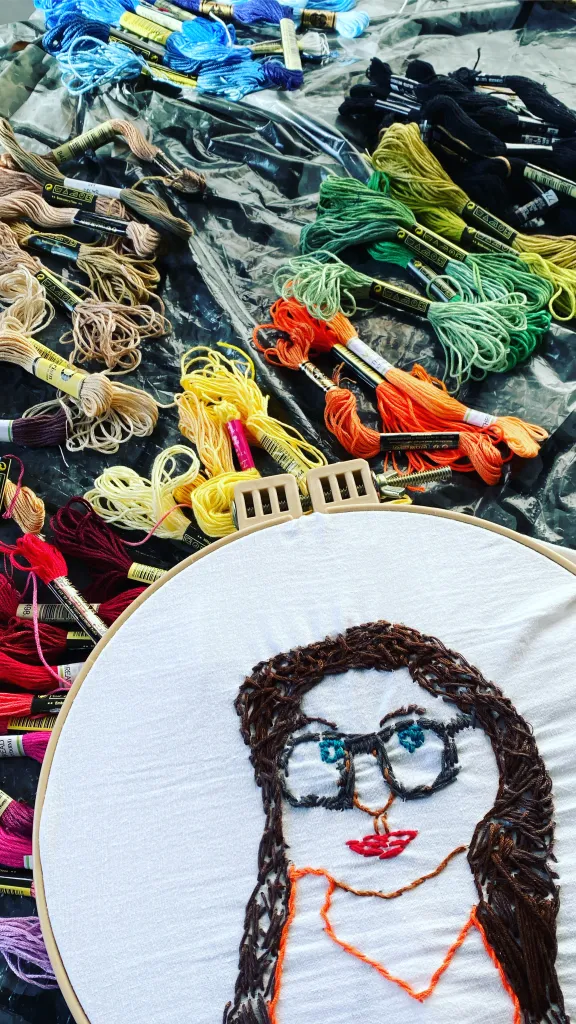 Embroidery floss of many colors and embroidery hoop with a portrait of a young woman 