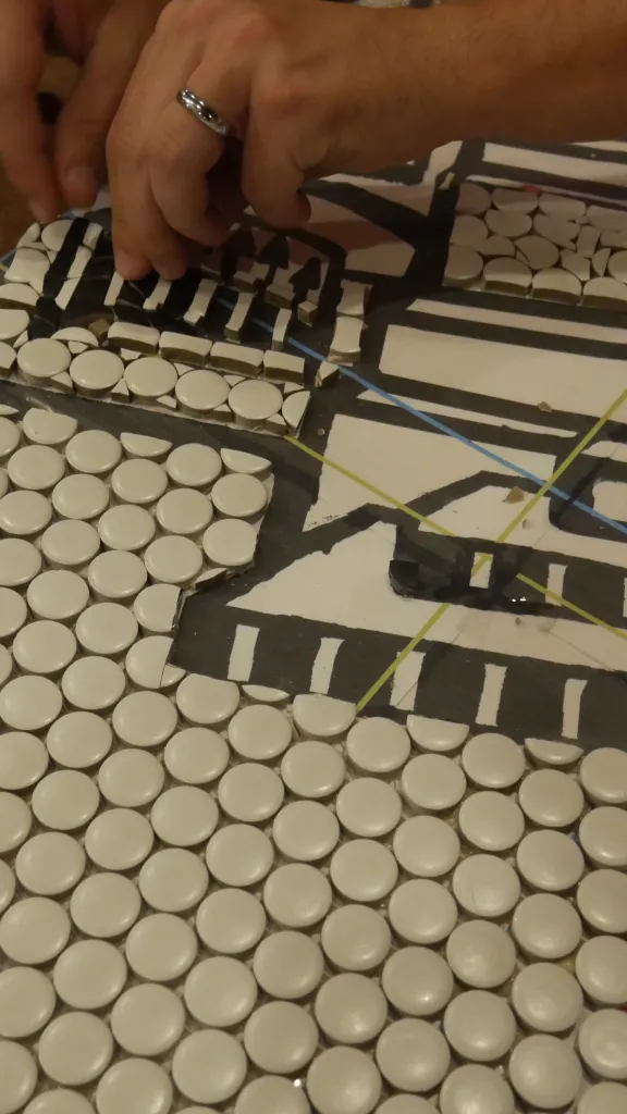 Image of someone's hands working on a tile mosaic at a previous Ministry of Awe event.