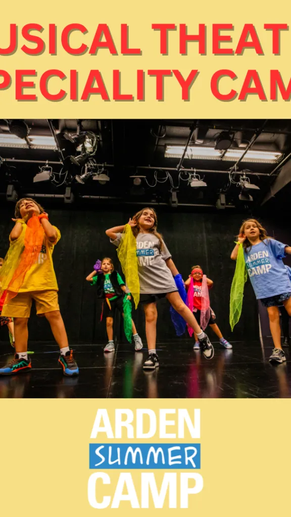 Campers dance and sing on stage facing the audience, holding colorful pieces of fabric