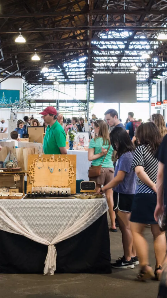 Interior view of Cherry Street Pier with people walking through the space, shopping at vendor booths, and browsing local goods