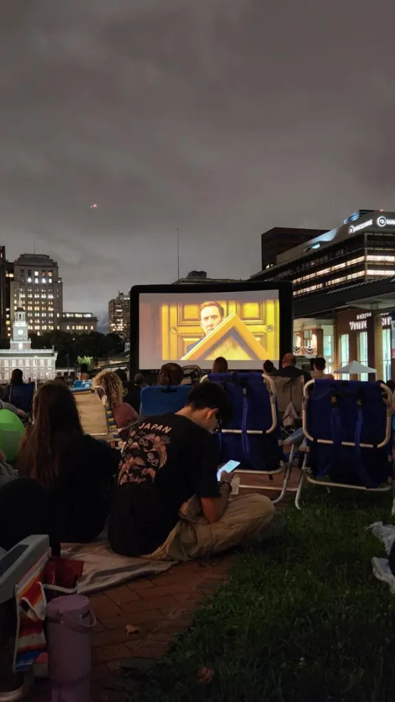 Guests in lawn chairs and on blankets watching a movie under the stars.