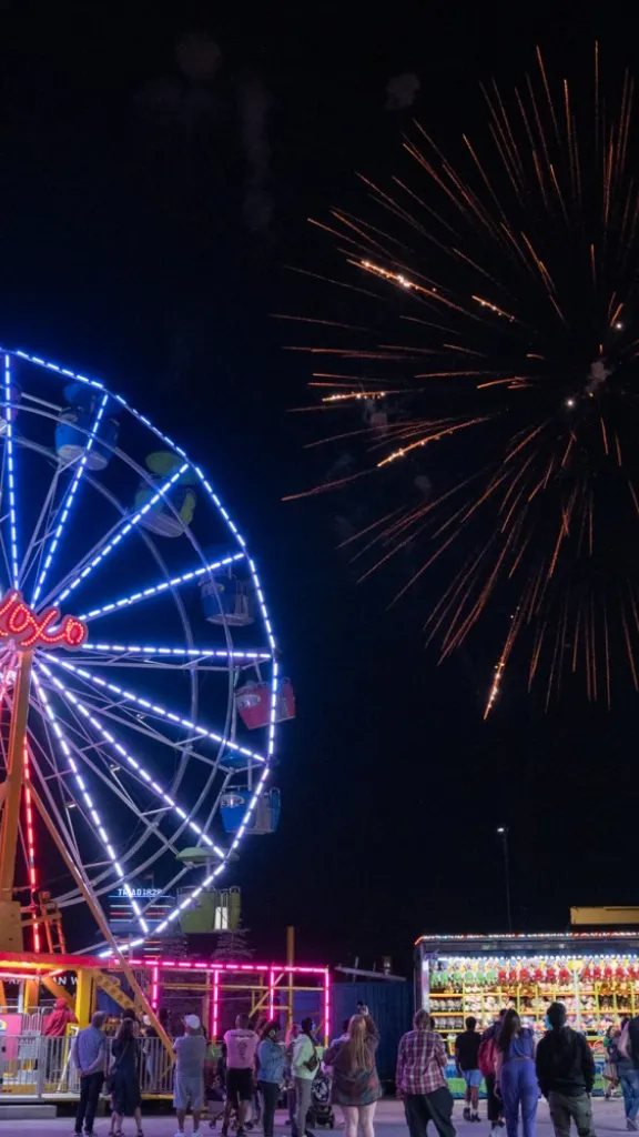 People gathered by Ferris wheel at Independence Blue Cross RiverRink watching fireworks.