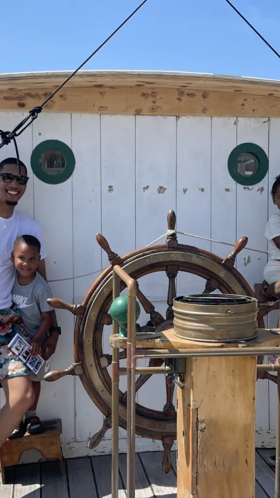 A family of 4 stands at the helm of Gazela Primeiro during a Free Deck tour