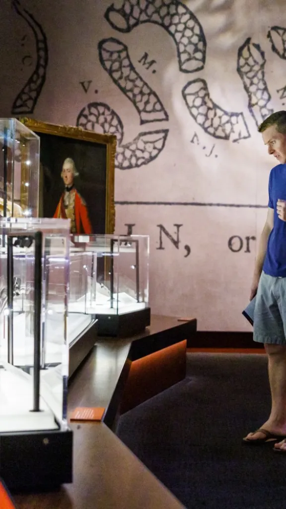 Visitors look at glass case display with Revolutionary War artifacts inside it