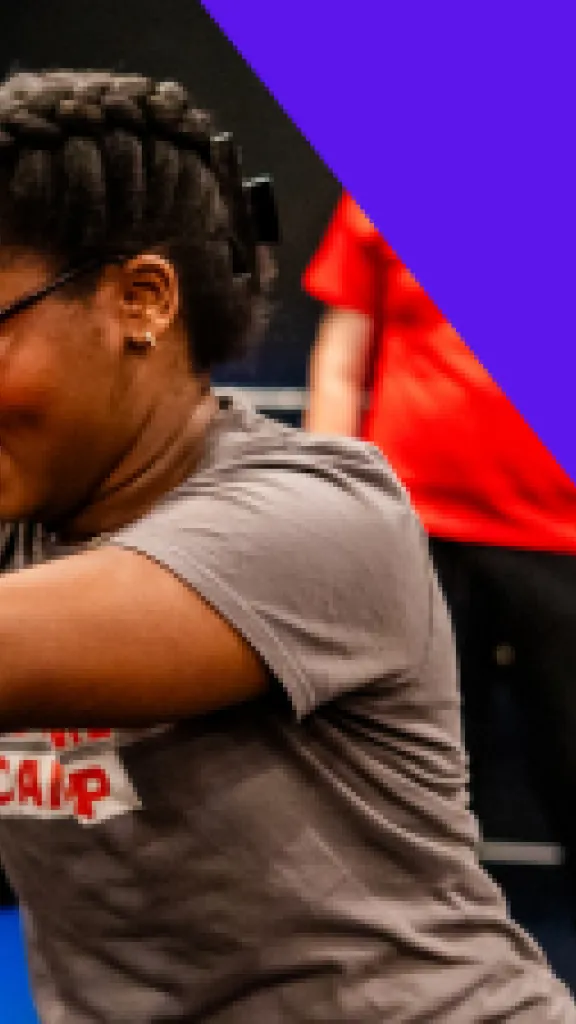 A girl in a gray shirt extends her arms outward, as if to push something. Other students watch behind her. Text that reads "One Day Workshop" and "Grades 6-8"