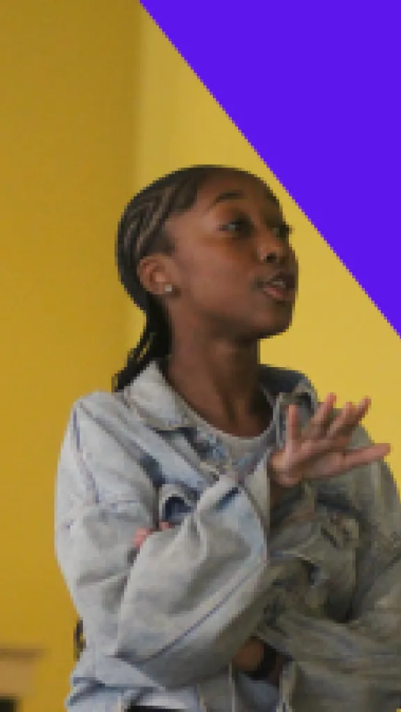 A girl in a gray hoodie and a girl in a black shirt with a heart on it act out a scene together in front of a yellow wall. The girl in the black shirt shows a confused face. Text that reads "One Day Workshop" and "Grades 6-8"
