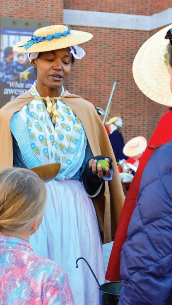 Living history interpreter talks with guests outside