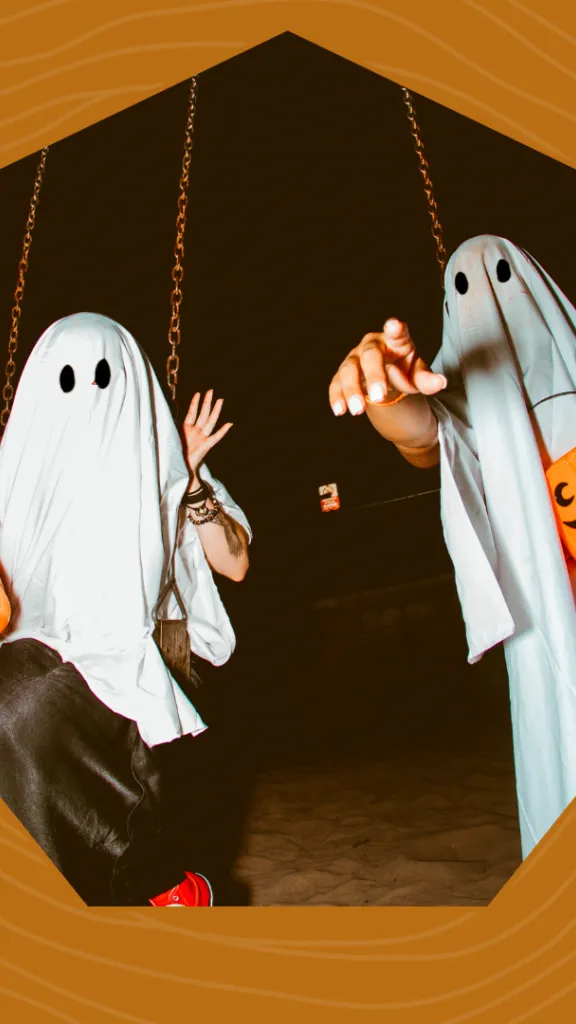 Two people in ghost costumes holding pumpkin trick or treat buckets