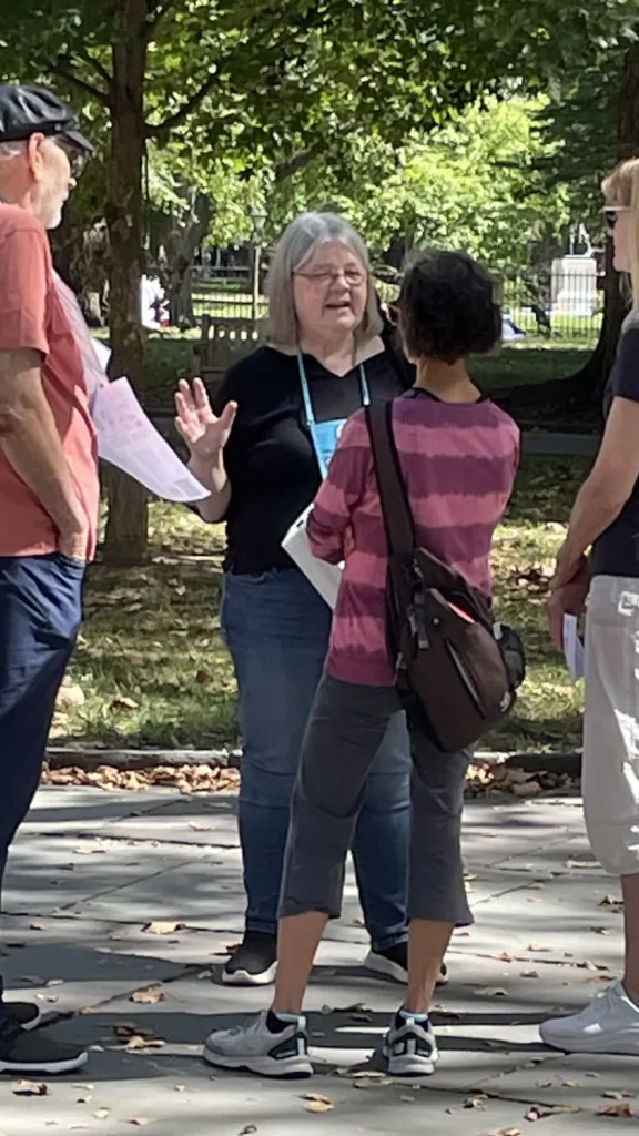 woman with blue lanyard speaks to a few people outside