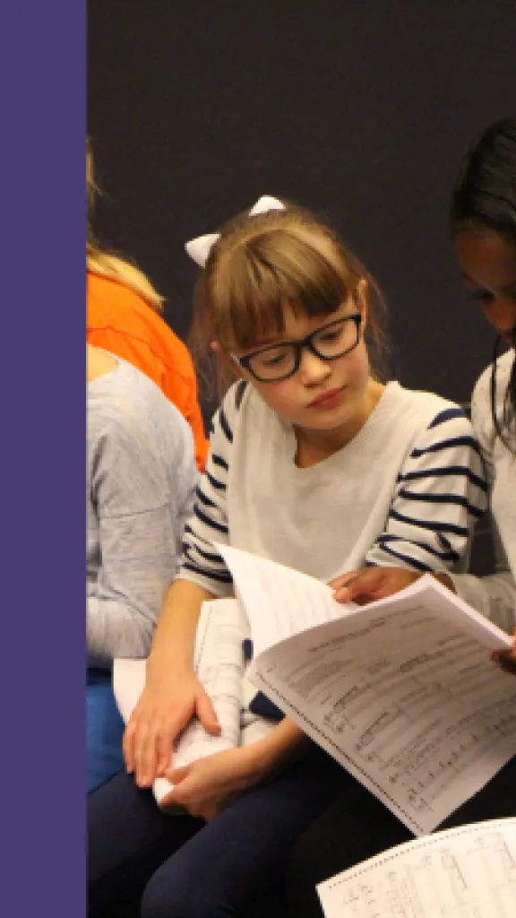 Three young students are sitting and holding sheet music, ready to sing! Next to the image, there is text that reads: 'Arden Summer Camp, Song Styles, One Day Masterclass for grades 9-12.'