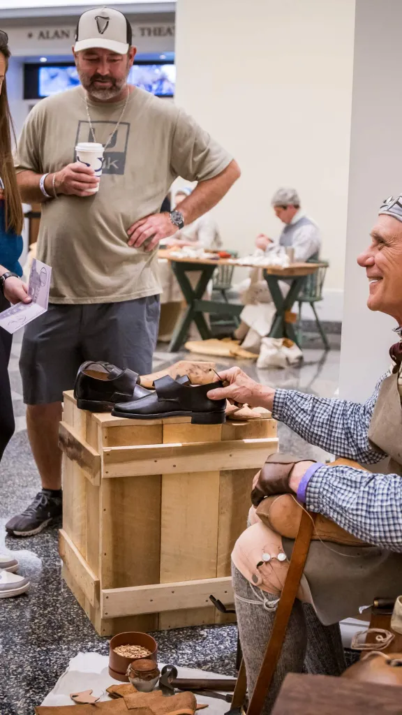 Older man dressed in Revolutionary outfit shows crowd 18th-century loafers