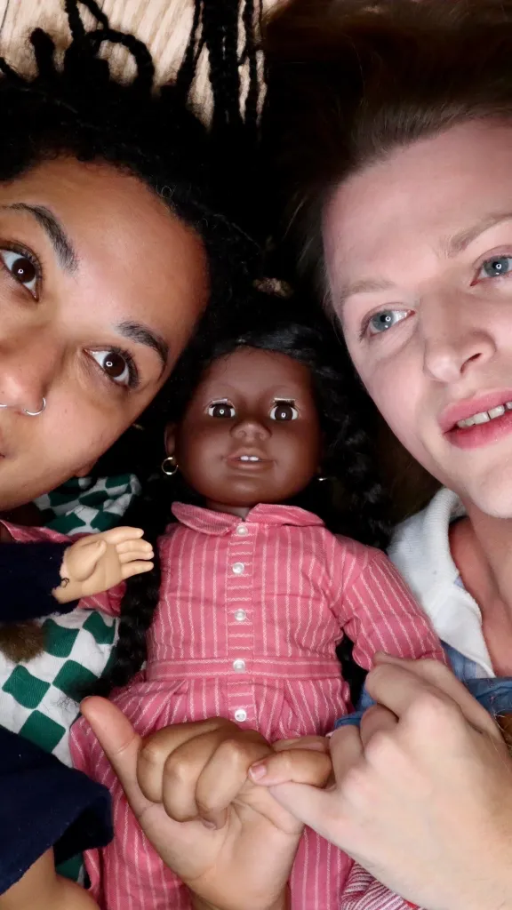 Jackie Soro and Pax Ressler laying down holding their American Girl Dolls.