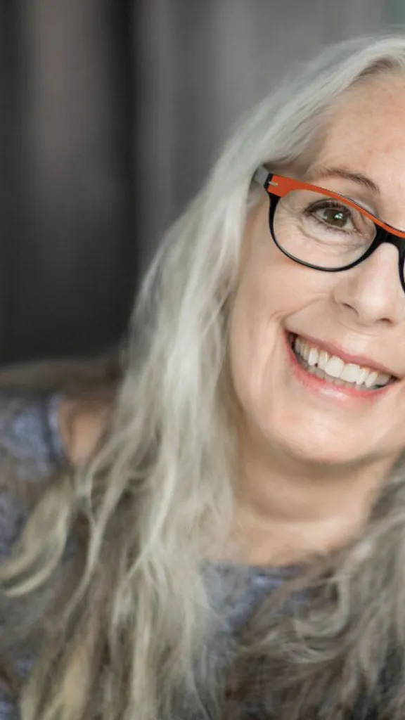 Graphic on left features books next to woman with grey hair and orange and black glasses