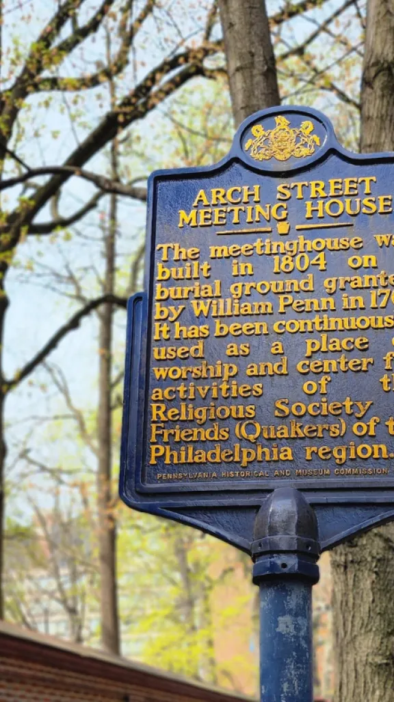Image of a blue historic marker in front of a red brick wall.