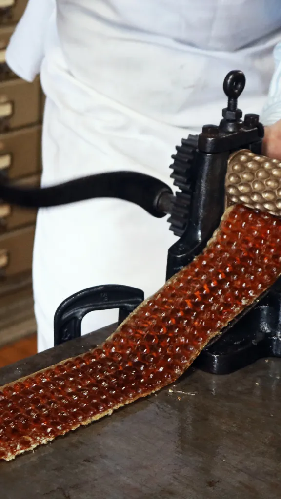hard candy being produced by an antique hand cranked machine