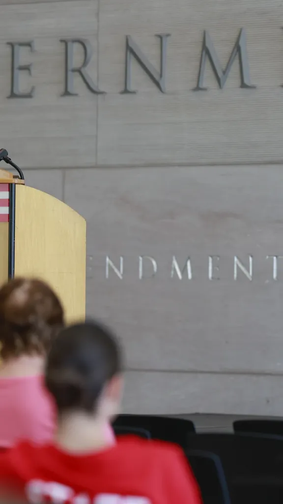 Woman presenting a program on a stage in a museum.