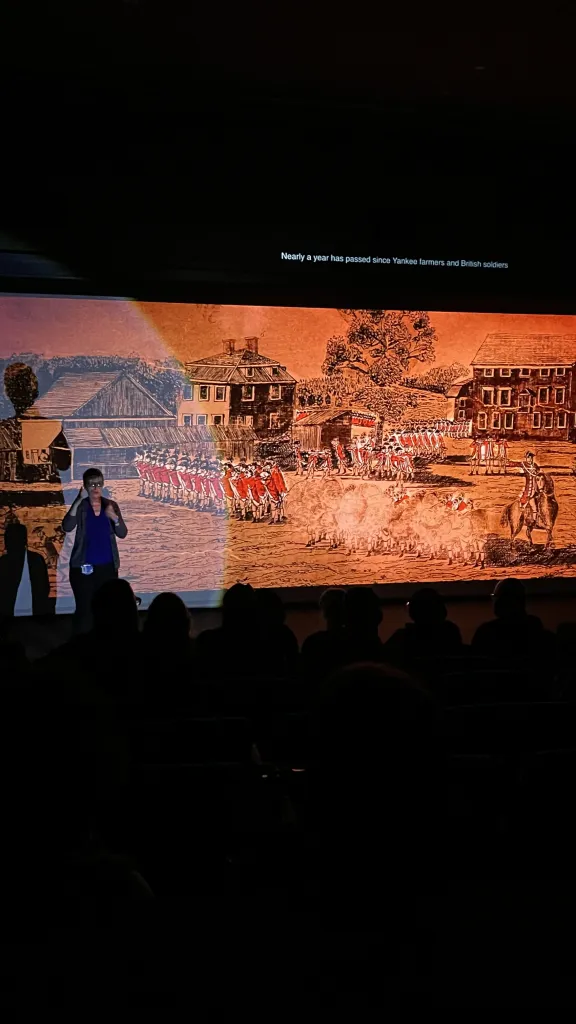 ASL interpreter stands in left corner signing during film screening