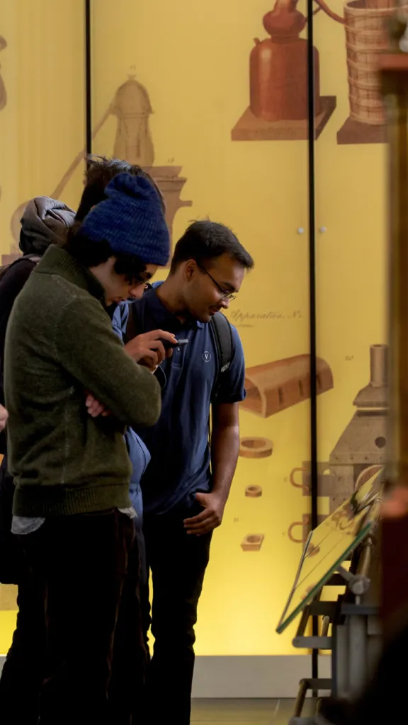Group of three people looking down at a display in the Science History Institute's museum. 