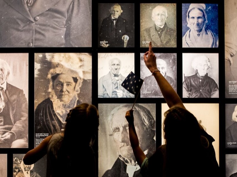 Adult and child looking at wall display of photographs at the Museum of the American Revolution