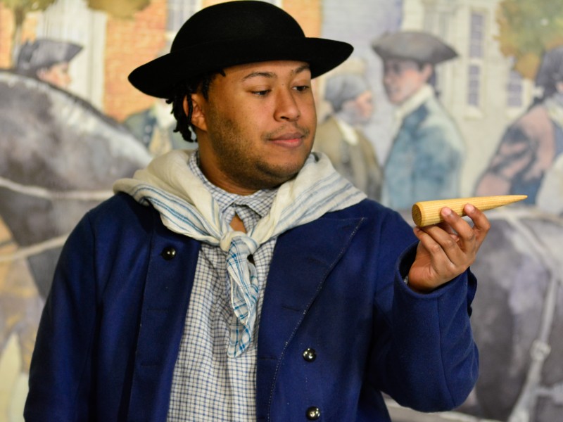 Actor Nathan Alford-Tate depicts a sailor in a blue coat holding a sailmaking fid in our Meet James Forten first-person theatrical performance.