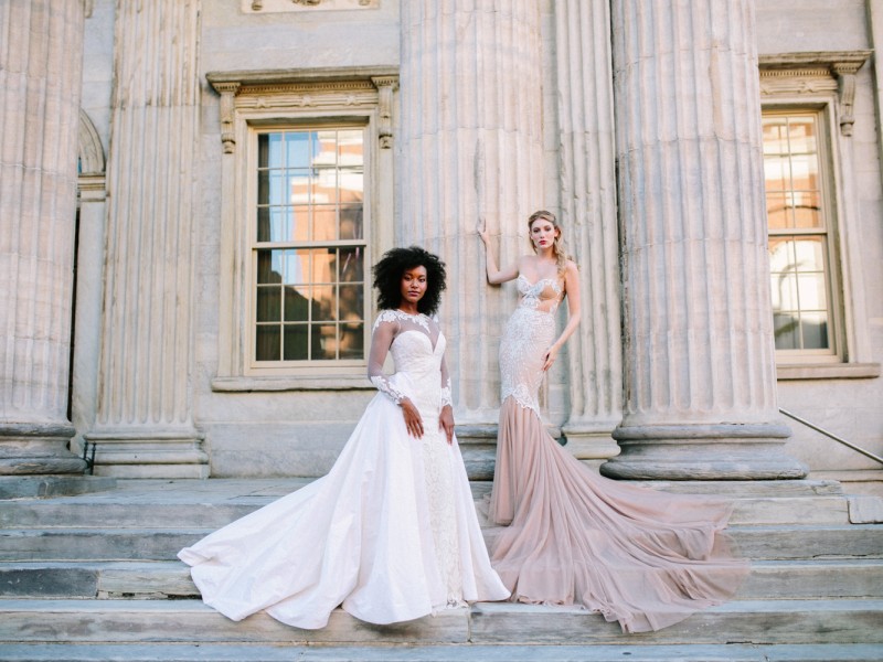 Two people wearing wedding gowns on steps