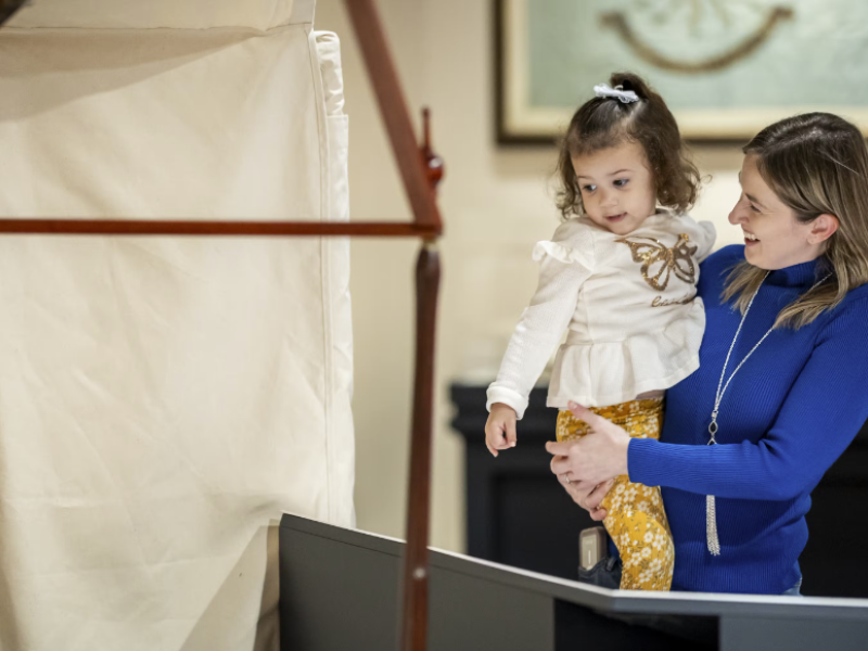Woman holding child looking at display in Witness to Revolution special exhibit.