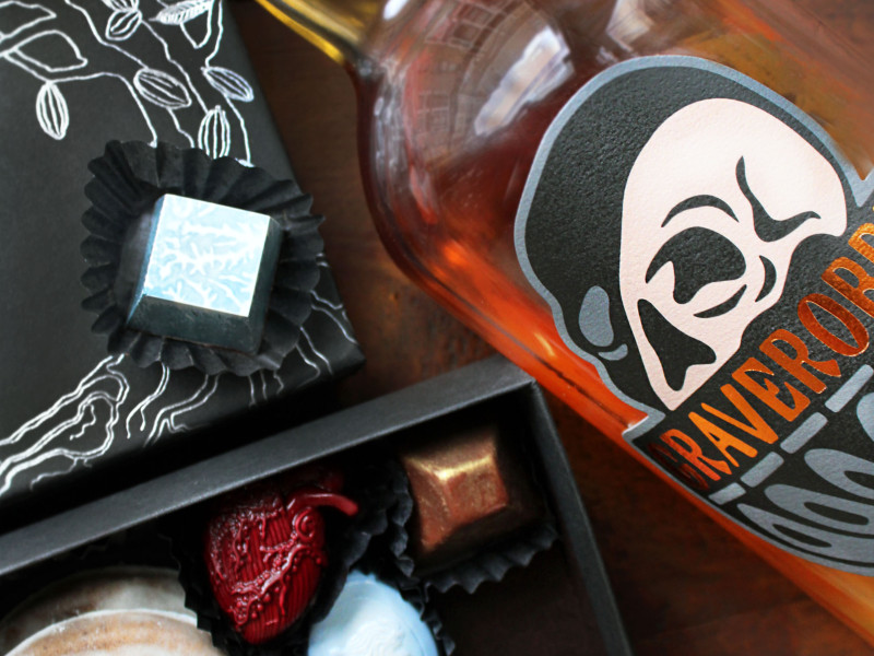 A bottle of Graverobber Unholy Rye Whiskey and a box of specialty chocolates