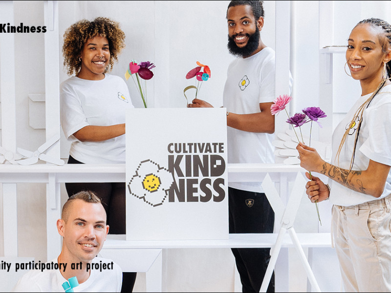 People holding colorful  paper flowers in a white market stand made out of cardboard.