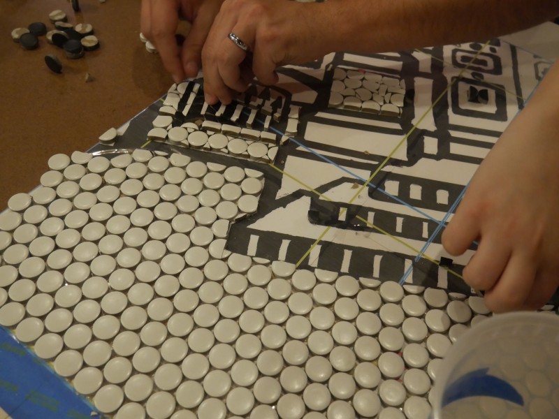 Image of someone's hands working on a tile mosaic at a previous Ministry of Awe event.