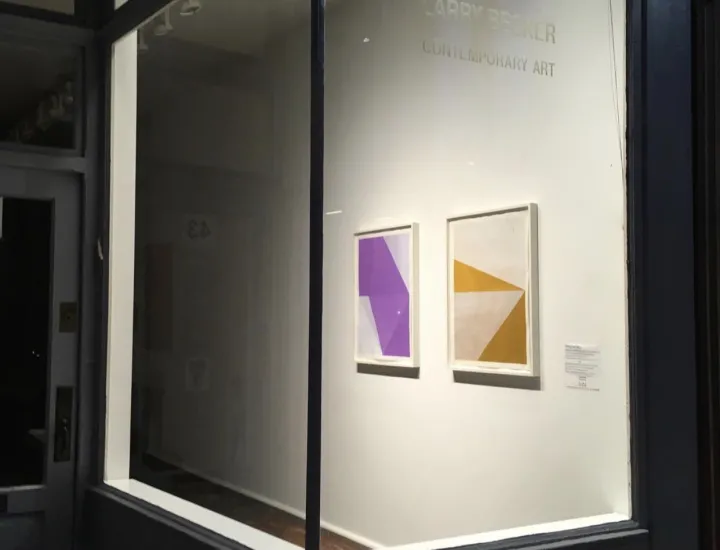 Exterior of art gallery of large window with view inside of artwork displayed on wall