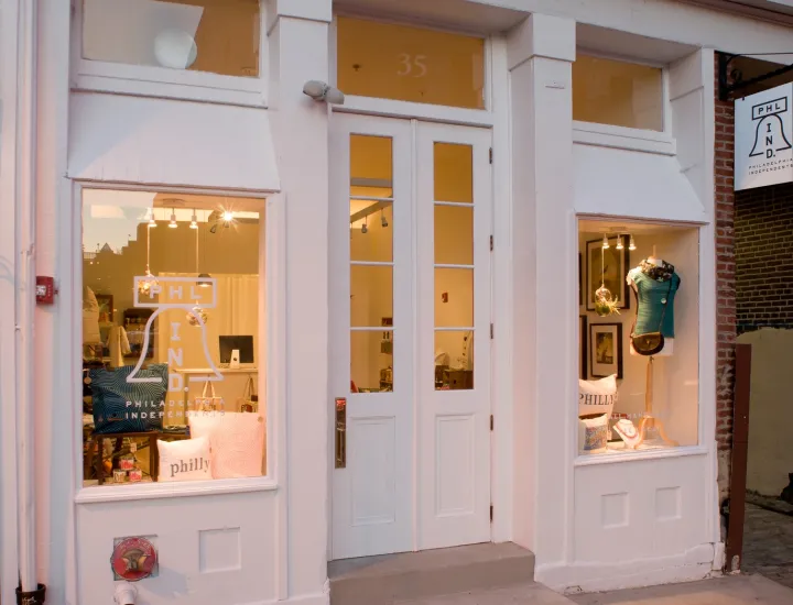 Exterior of store front with two windows of merchandise displays and a door in the middle