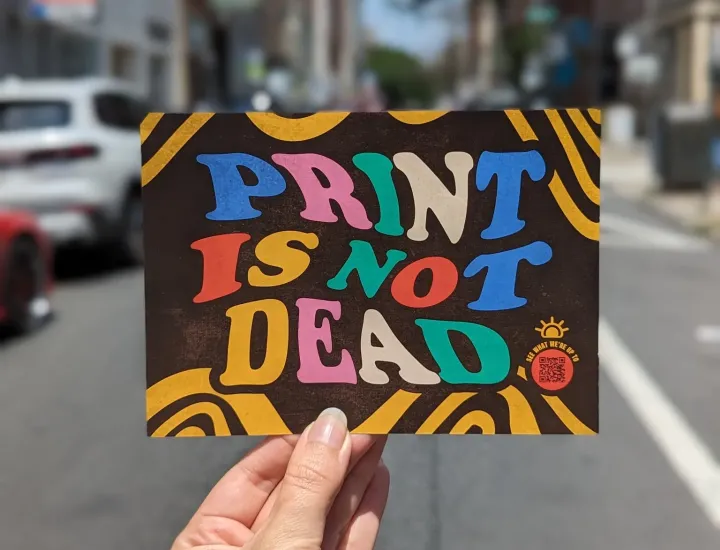Person holding flyer that says "Print is not dead"