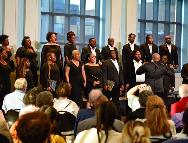 Chorale of men dressed in suits and women dressed in black dresses sing