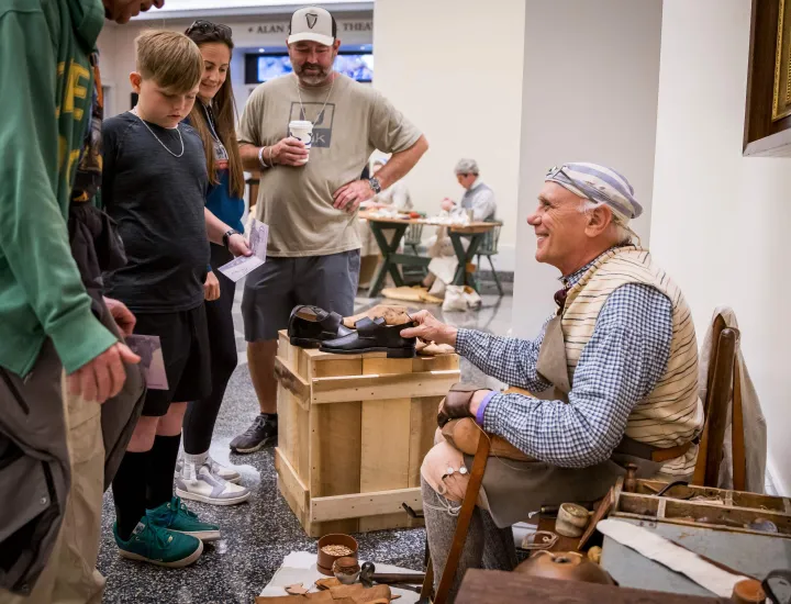 Older man dressed in Revolutionary outfit shows crowd 18th-century loafers