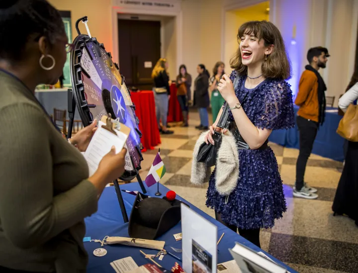 Woman with brown hair and navy blue dress smiles