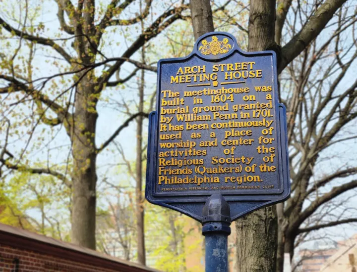 Image of a blue historic marker in front of a red brick wall.